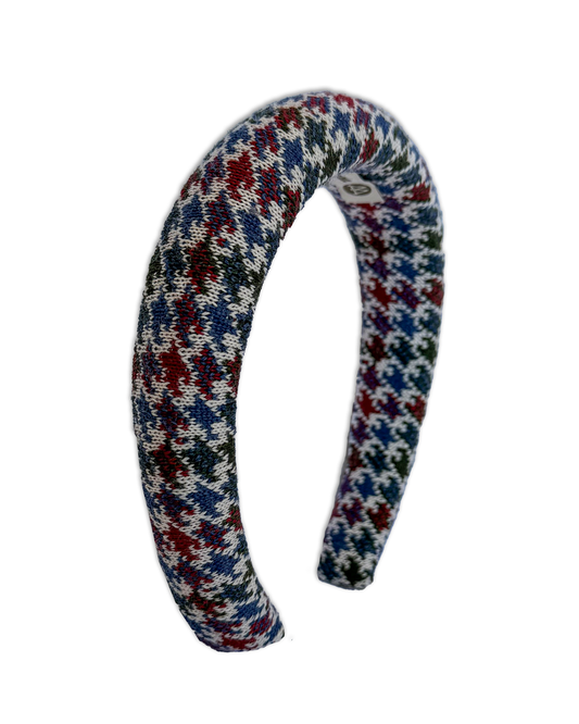 A curved knit headband featuring a multicolor houndstooth pattern with red, blue, green, and white yarn, shown against a plain white background.